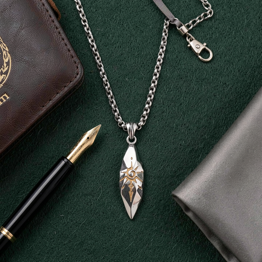 Sigil Quicksilver necklace arranged on a green desk beside a pen
