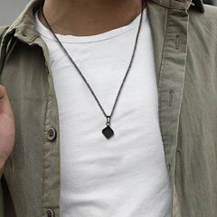 Cube Black necklace worn over a white shirt with an olive overshirt