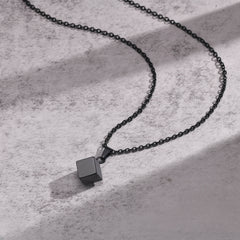 Cube Black necklace arranged on a light concrete surface