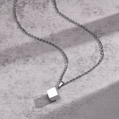 Cube Silver necklace arranged on a light concrete surface