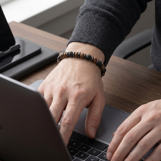 Relic bracelet worn at a laptop in soft office light
