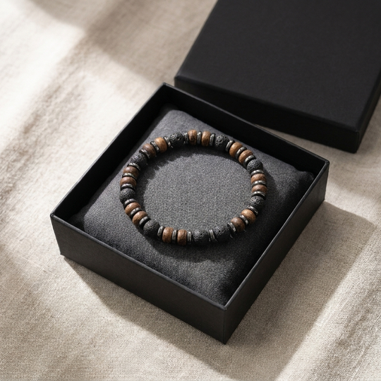Relic bracelet coiled in a matte black gift box on linen