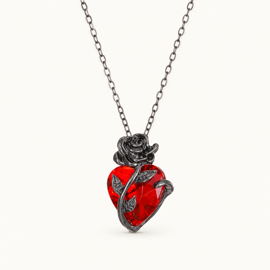 Crimson red heart and dark rose necklace on a warm white background