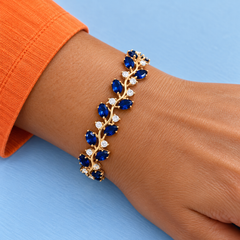 Close worn view of Eden in Cobalt with a gold-tone finish beside a tangerine sleeve.