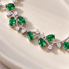 Close detail of Eden’s green cubic zirconia leaves, fine silver-tone vine and small clear accents.