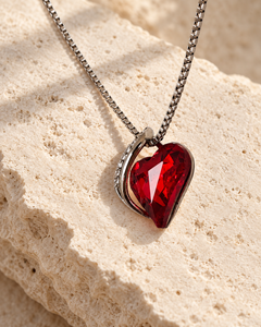 Embrace Scarlet heart necklace resting on pale stone