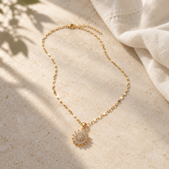 Flora Gold necklace on pale stone in soft morning light