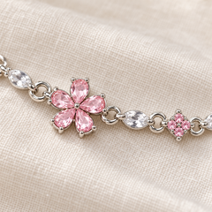 Close-up of Floret's five pink petals, clear stone, four-stone pink cluster and round silver-tone links
