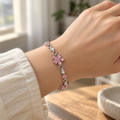 Floret worn beside a cream cuff, showing its five-petal pink flower at natural wrist scale