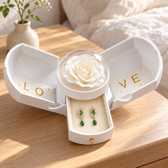 Iris Forest Gold earrings in the white Rose Box, styled open on a bedroom table in soft morning light