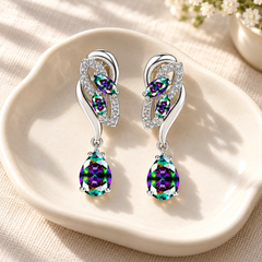 Iris Spectrum earrings with iridescent rainbow stones, styled on an ivory tray with cream linen