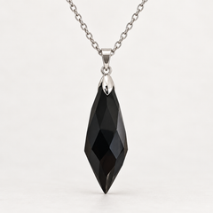 Meteor Black faceted pendant, centred silver-tone fitting and fine chain on a light background