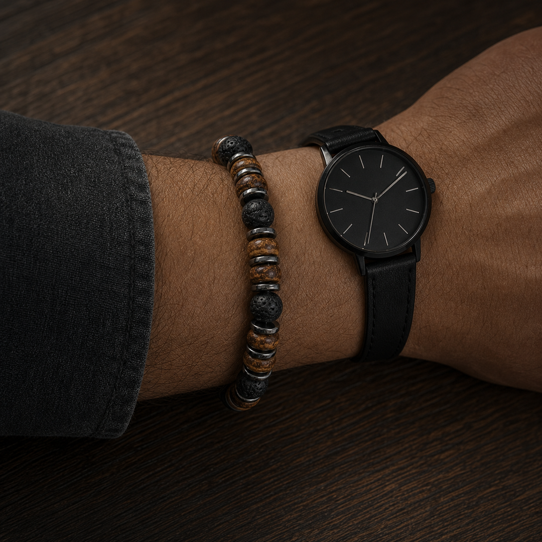 Relic Ash bracelet paired beside a black leather-strap watch on a dark oak table